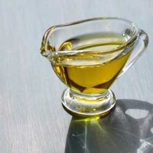 Golden olive oil in a small glass pitcher, highlighting its clear texture and rich color.